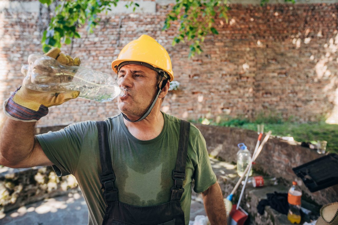 Outdoor worker drinks water in the shade 