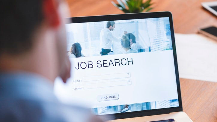 A man is looking at a job search page on a laptop.