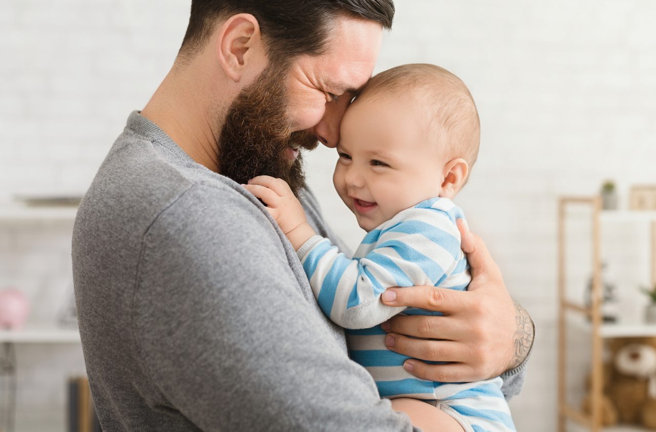 A father holding his infant at home.