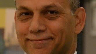 A man in a suit and tie smiles for the camera.