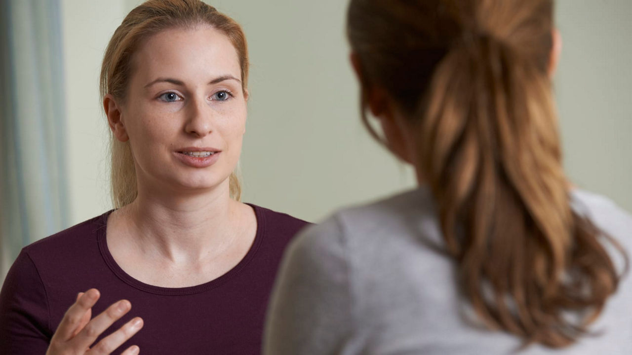 A woman talking to another woman in a room.