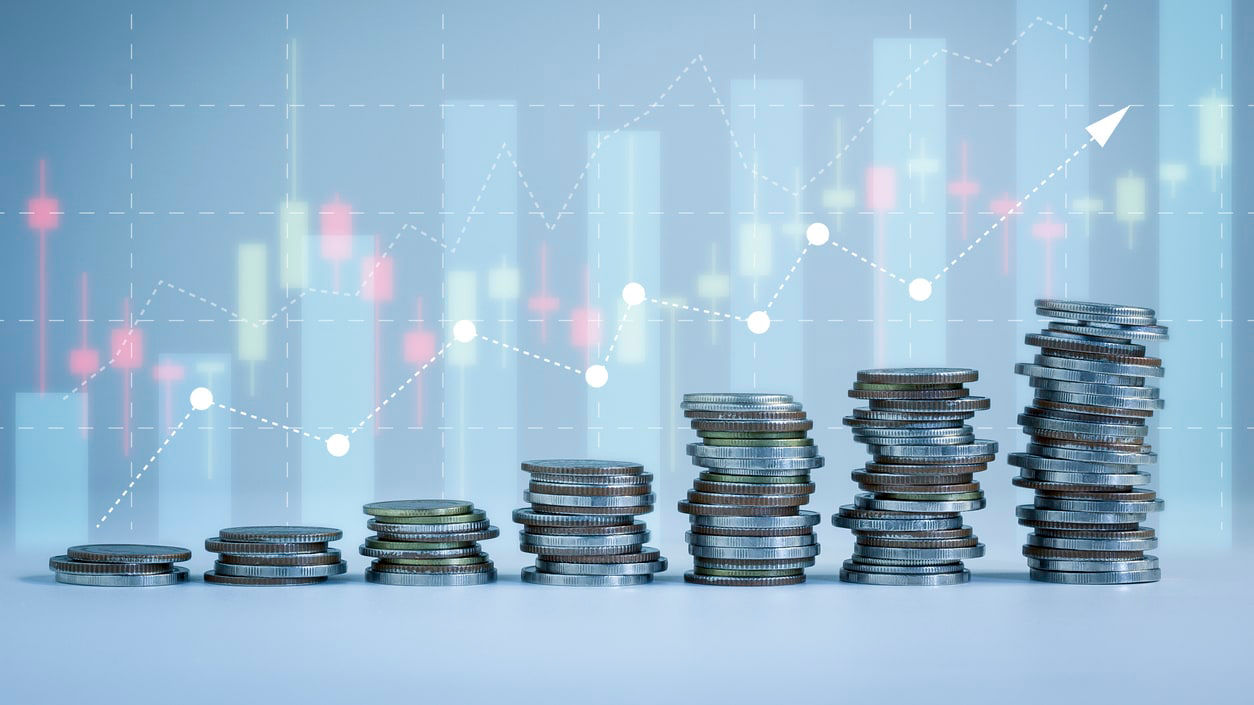 A stack of coins in front of a graph.