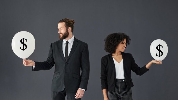 Businessman and woman holding balloons with dollar signs.