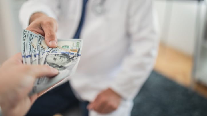 A doctor is handing money to a patient.