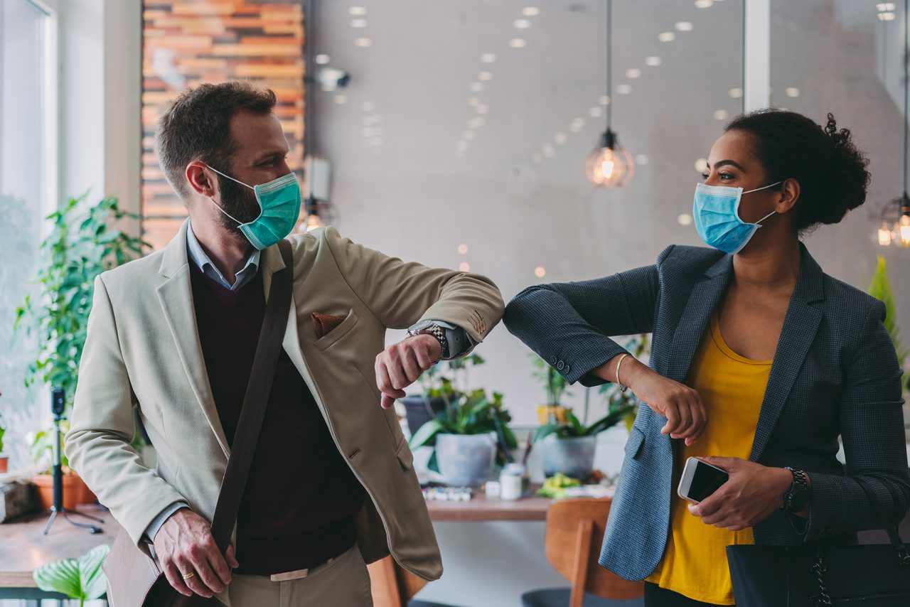 Two employees with masks on bumping elbows.