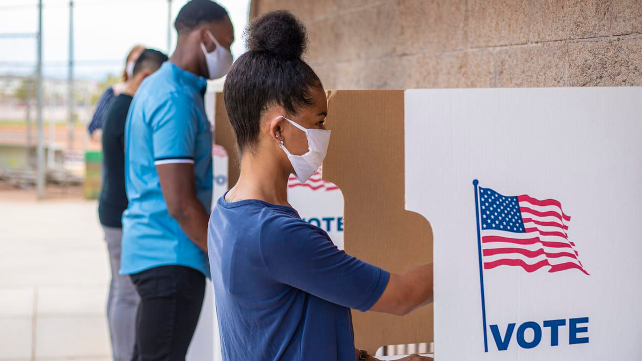 A group of people voting in a voting booth.