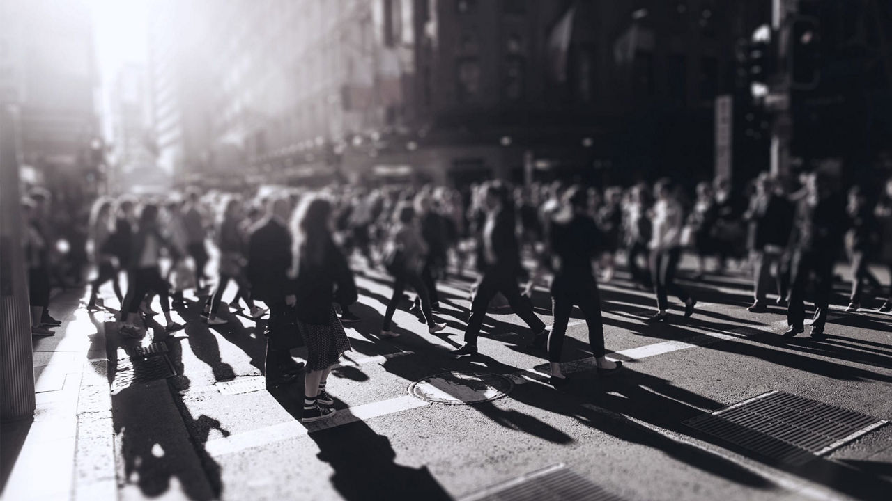 A group of people crossing a street in a city.
