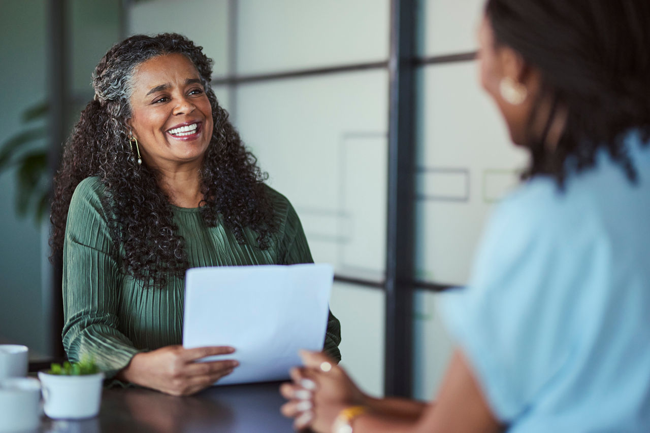 Two Black women having an upbeat office conversation.