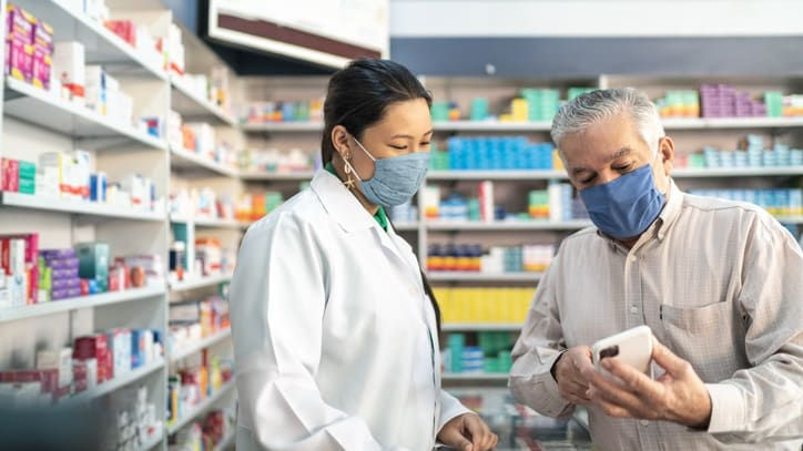 A man and woman in a pharmacy looking at a tablet.