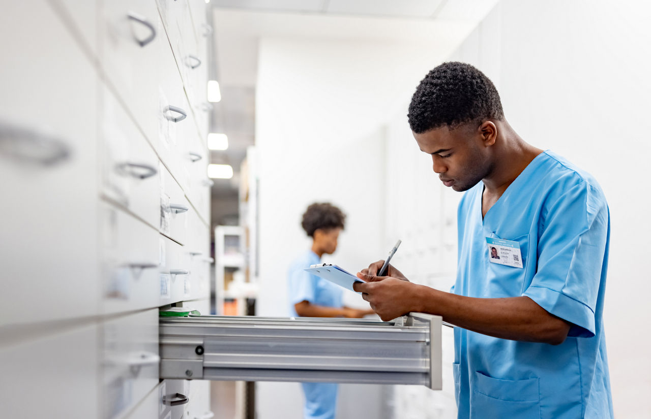 African American nurse taking inventory of medicines at the hospital pharmacy - healthcare and medicine concepts