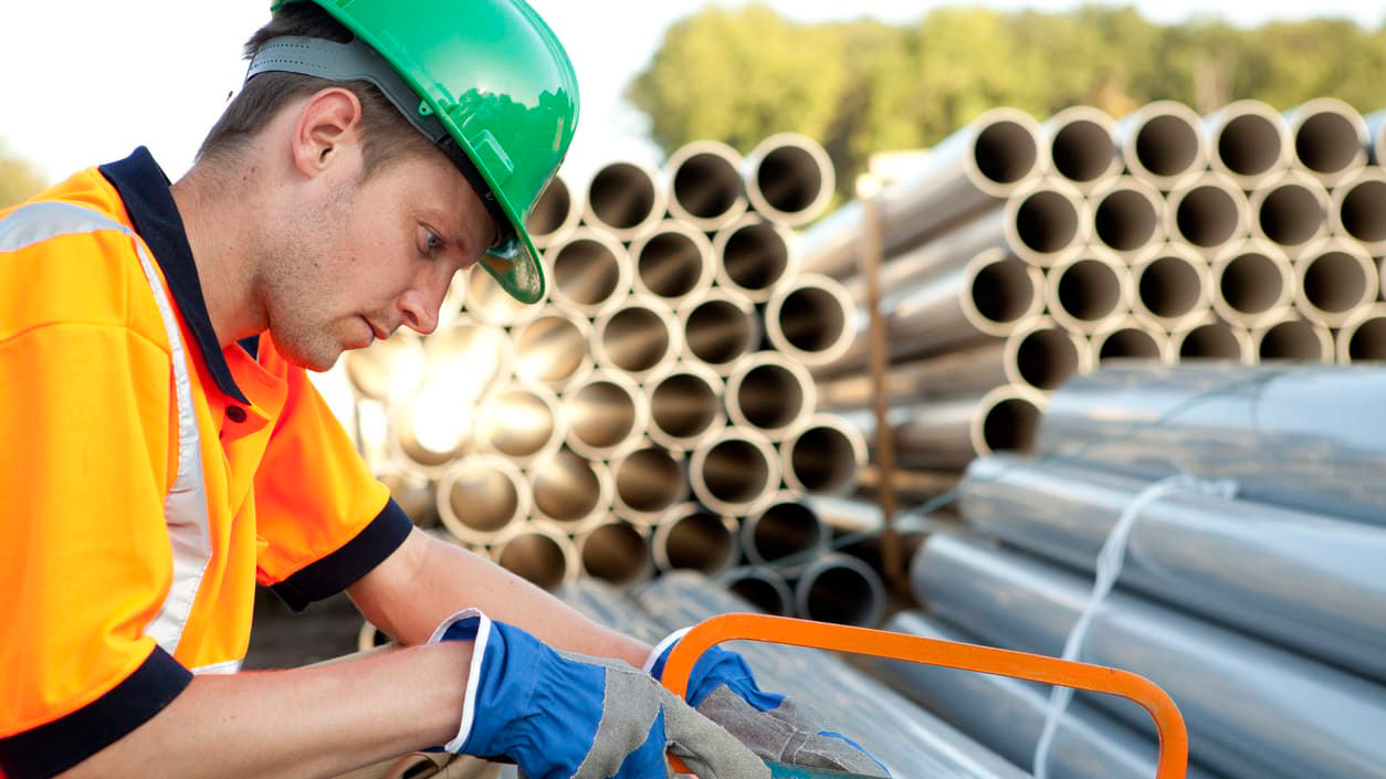 A construction worker is working on a pipe.