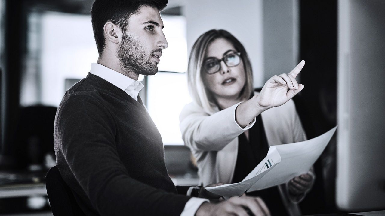 two employees pointing at computer screen