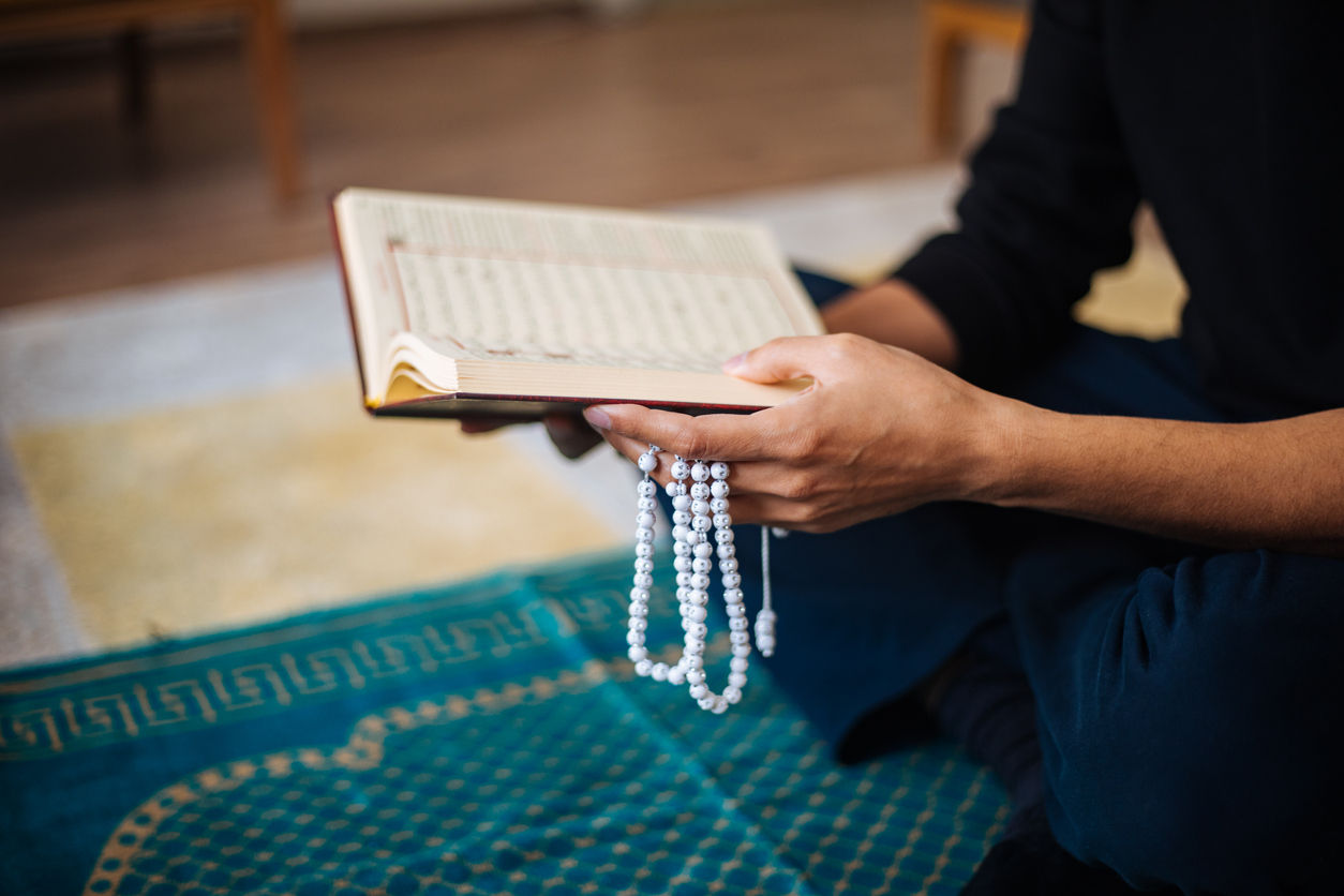 Person praying with prayer book and beads