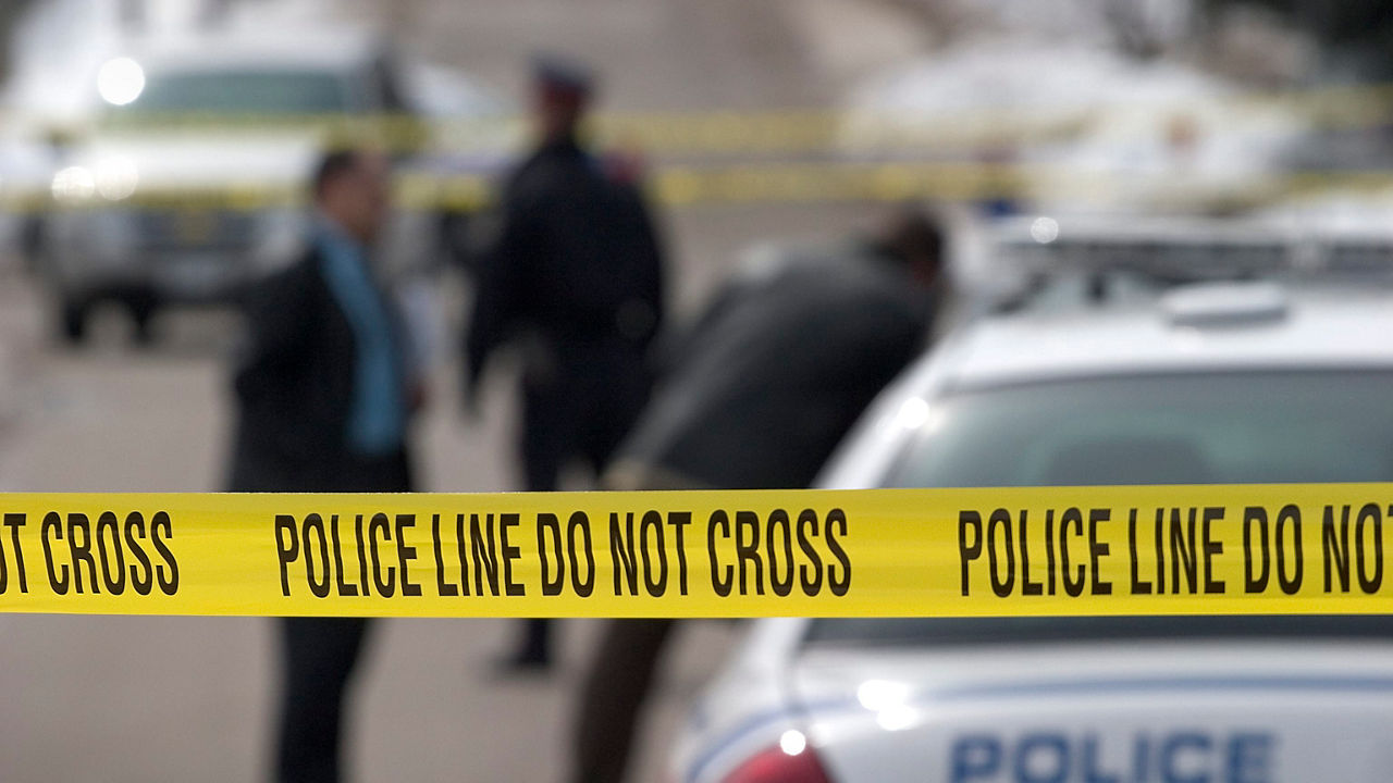 A police tape with a police officer standing next to it.