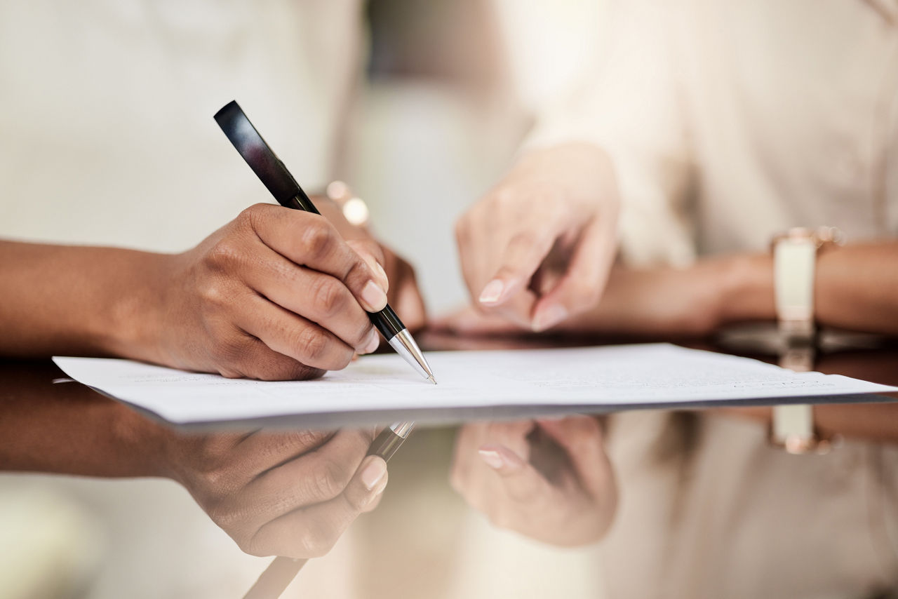 Hands signing a document