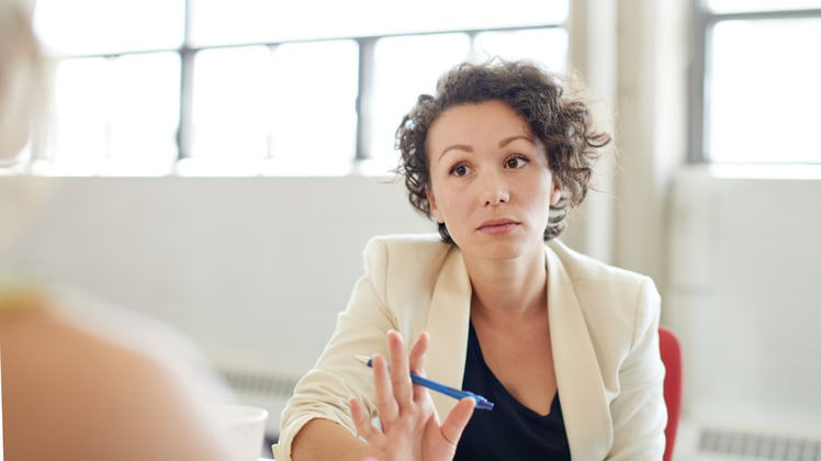 A woman is talking to another woman at a meeting.