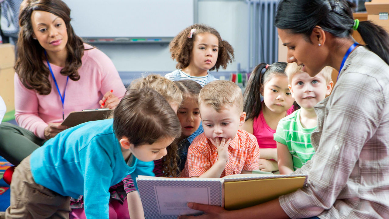 A teacher reading to children in a classroom.