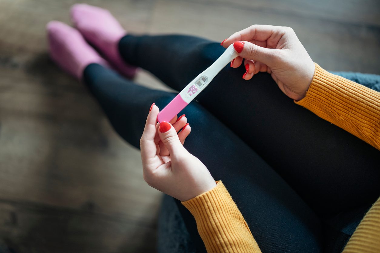  woman holding a positive pregnancy test