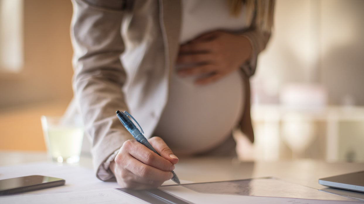 A pregnant worker writing