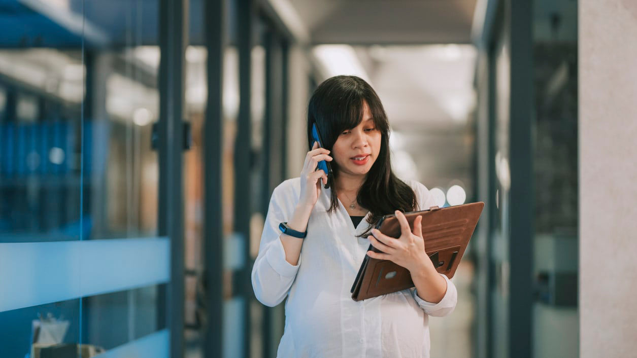 Asian female doctor talking on the phone while standing in an office.