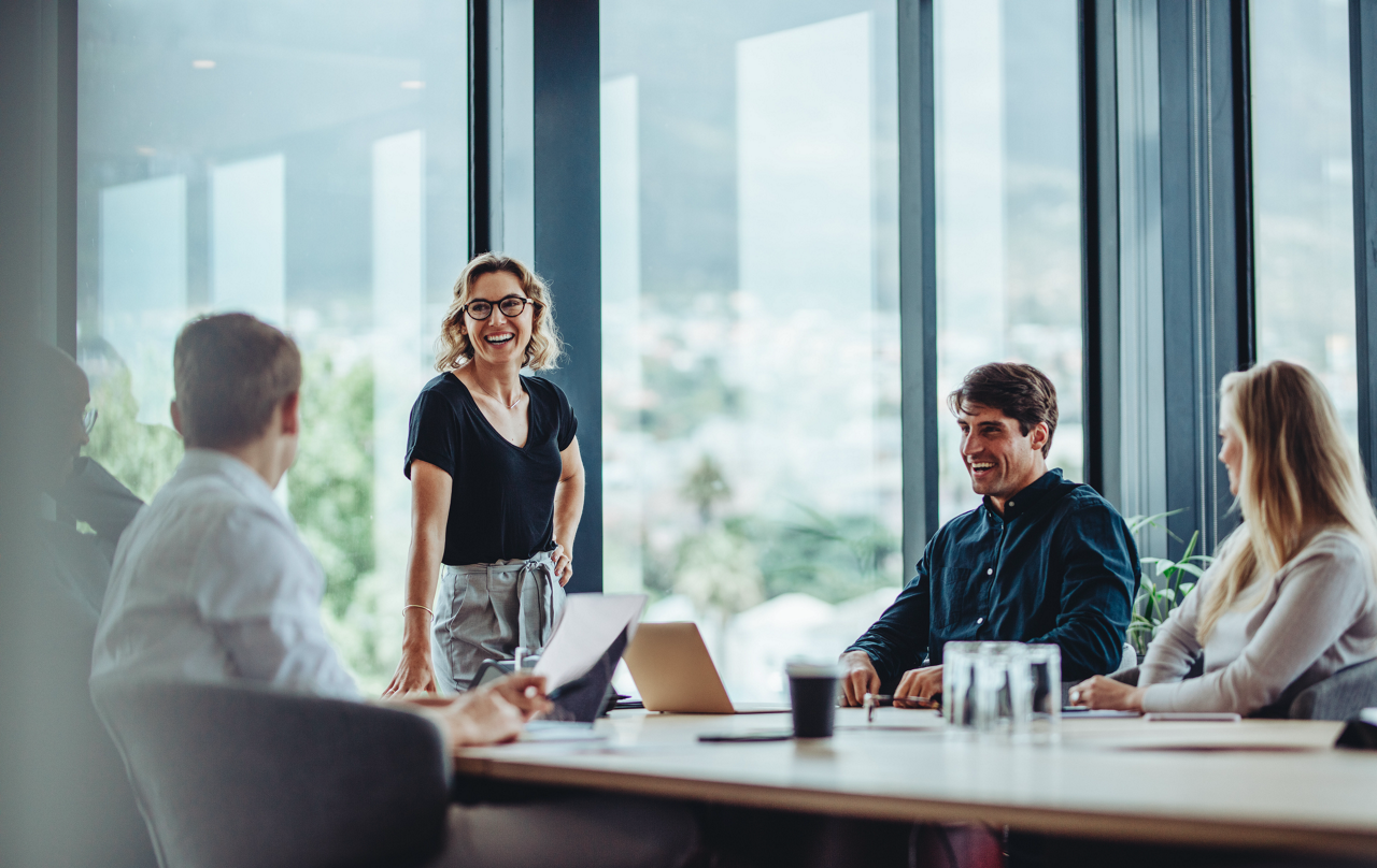 Office colleagues having casual discussion during meeting in conference room. Group of men and women sitting in conference room and smiling.