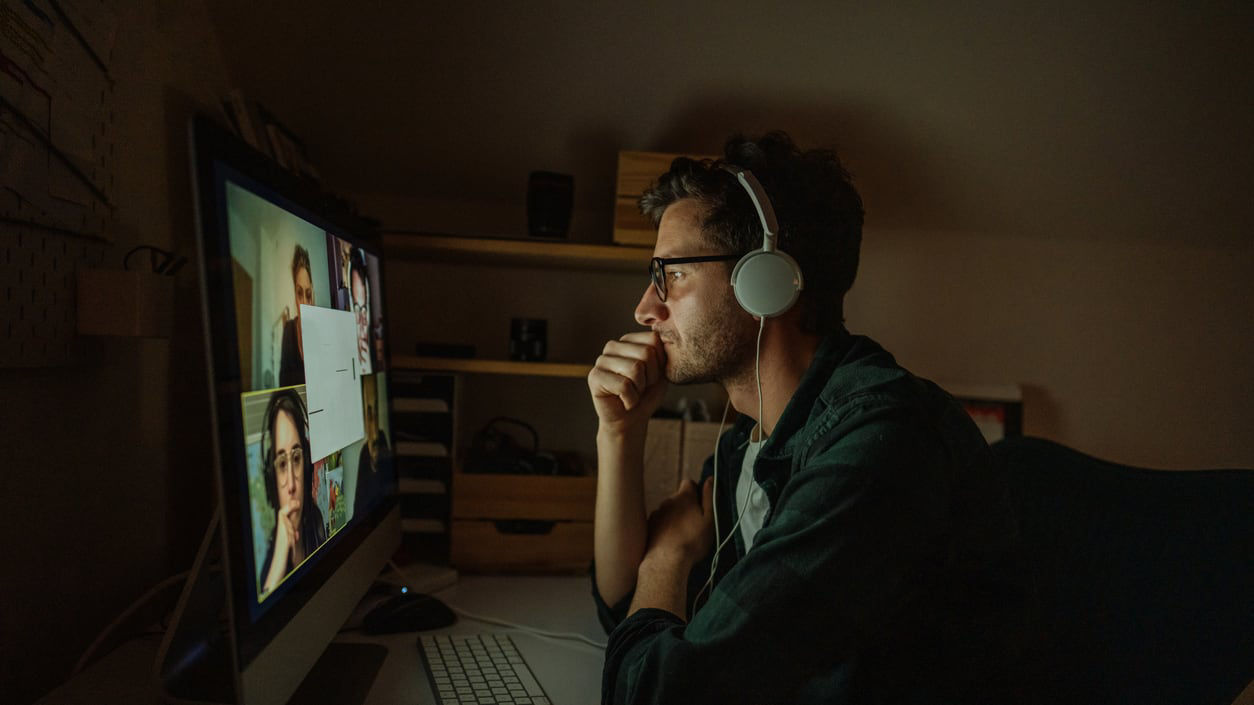 A man sitting in front of a computer with headphones on.