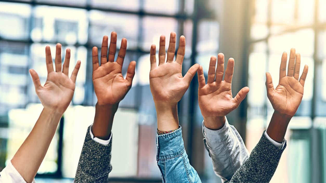 A group of people raising their hands in the air.