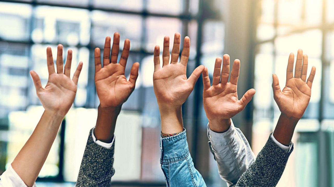 A group of people raising their hands in the air.