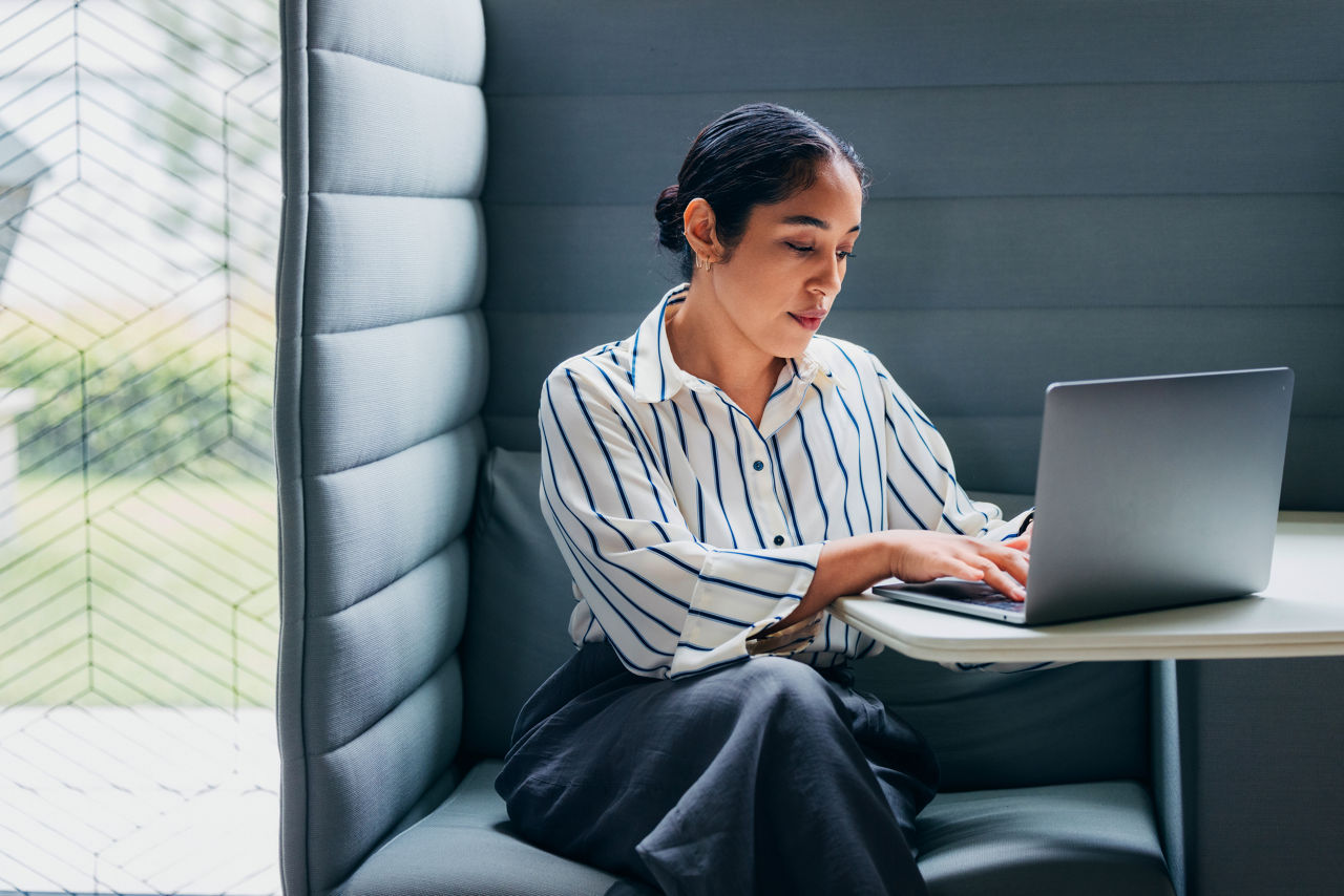 A concentrated woman diligently using a laptop in a private, modern office workspace. Ideal representation of productivity, focused work, and contemporary business environments in today's professional landscape.