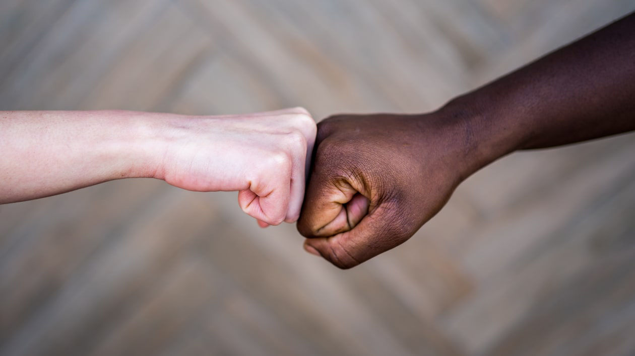 A man and a white woman are fist bumping each other.