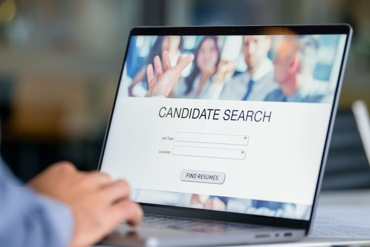 Close up of a Businessman looking at recruitment website on a laptop computer. Candidate search page with job type and location buttons. The mans hands can seen working on a keyboard.