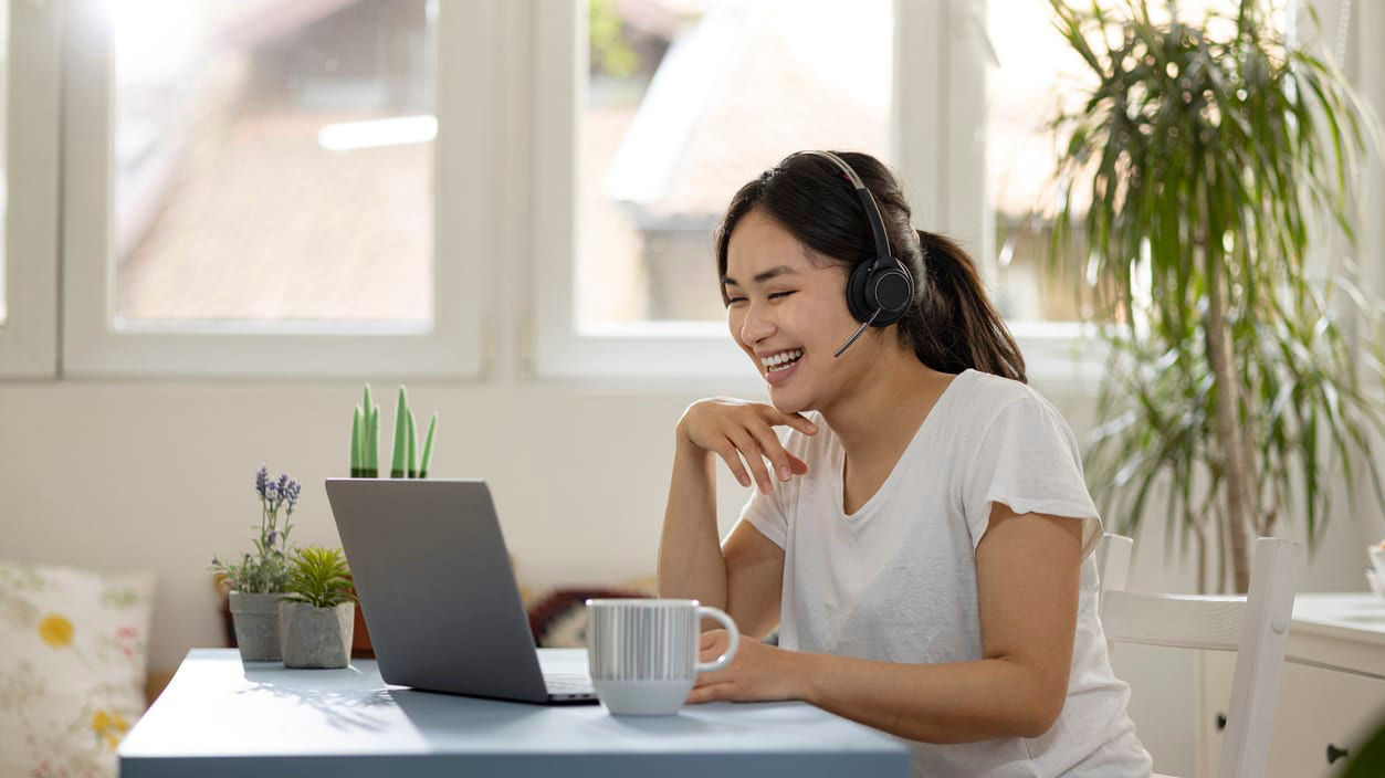 A woman wearing headphones is sitting at a table with a cup of coffee.