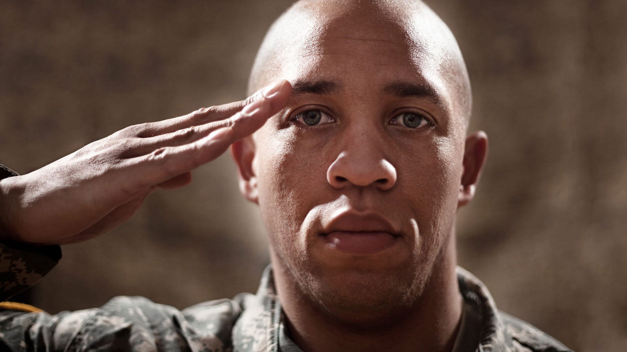 A soldier in uniform saluting his head.
