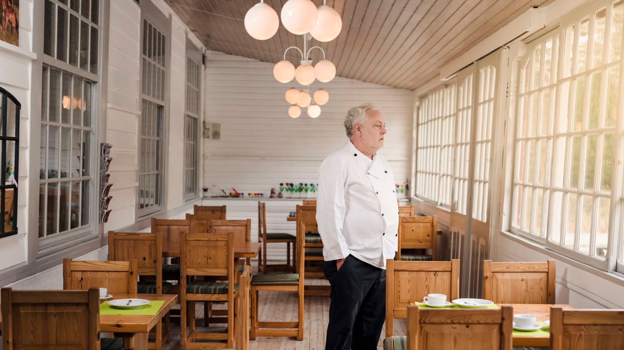 A man in a chef's uniform standing in a restaurant.