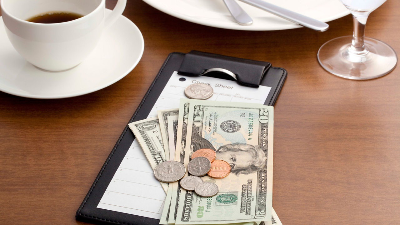A clipboard with money and a cup of coffee on a table.