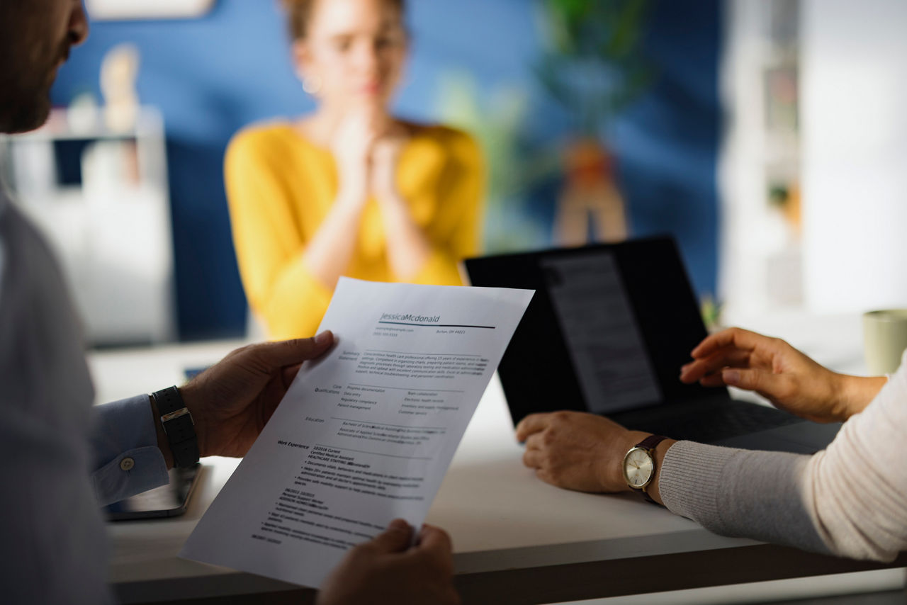 Close up of unrecognizable member of human resource team going through candidate's resume during a job interview in the office.