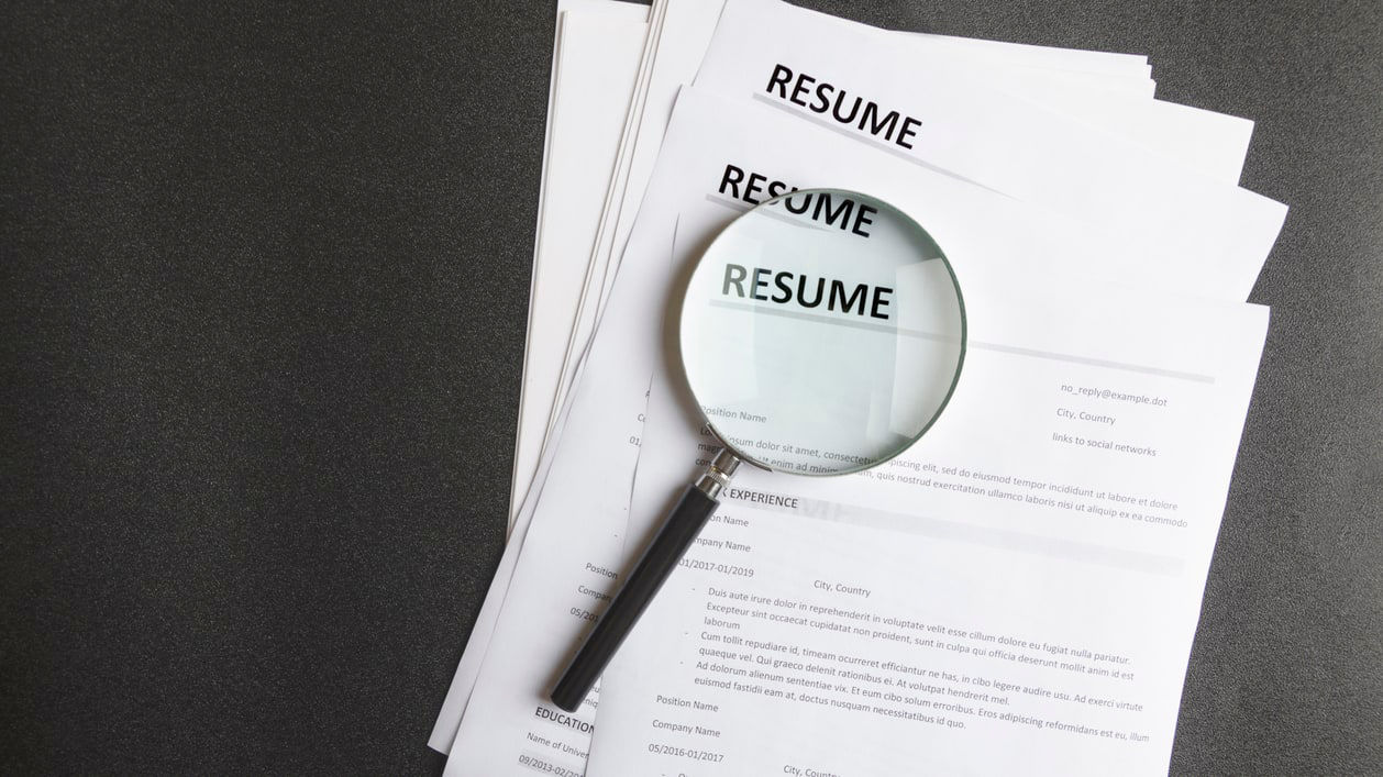 A magnifying glass is placed on top of a resume.