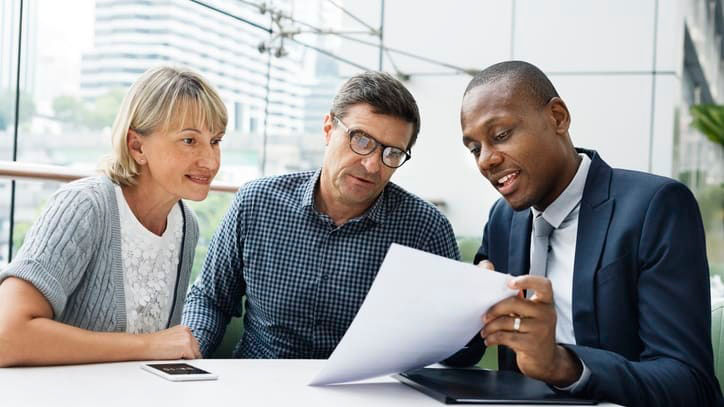 Three business people looking at a piece of paper.