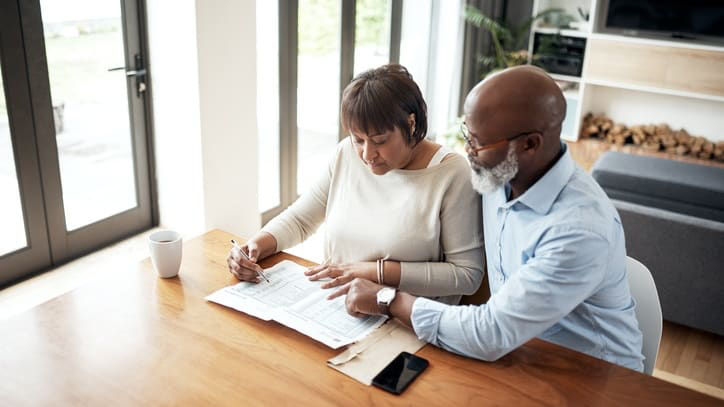 A couple looking at paperwork at a table in their home.