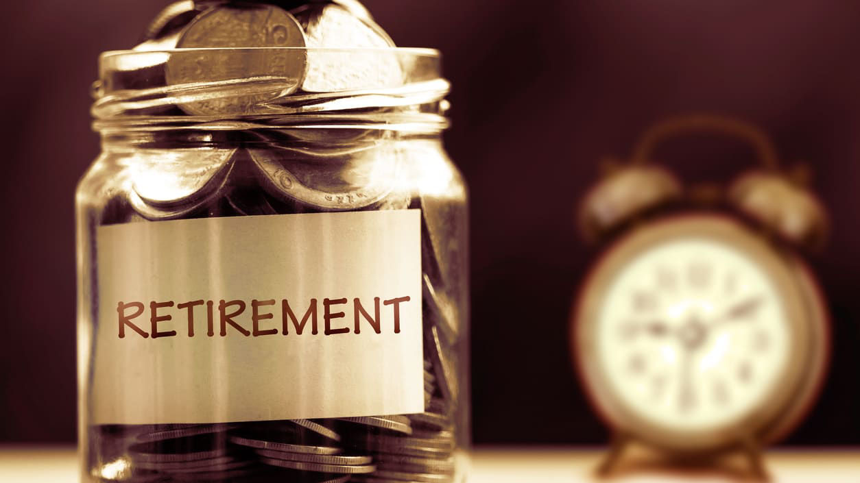 A jar with coins next to an alarm clock.
