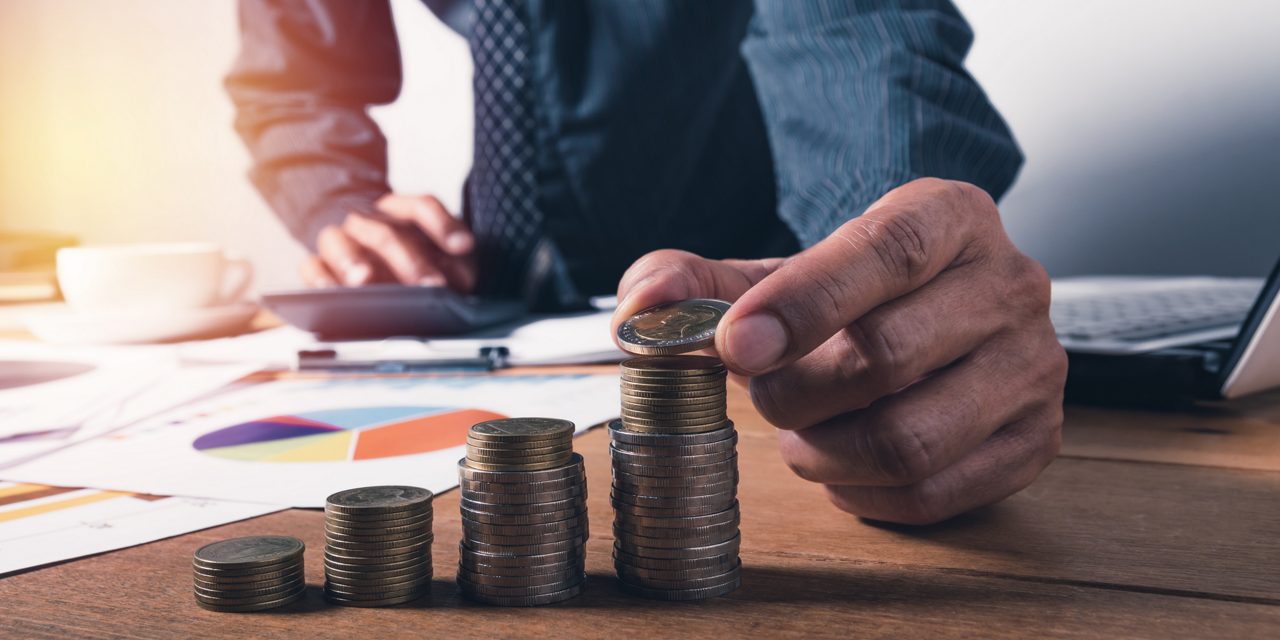 man adding to collection of coins on desk
