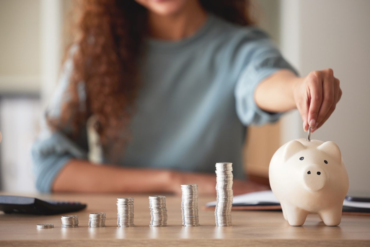 woman putting coins in piggy bank, indicating future savings