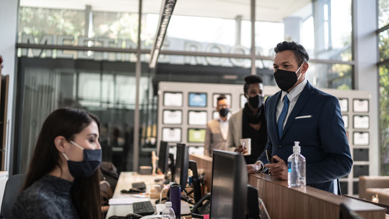A group of people wearing face masks in an office.