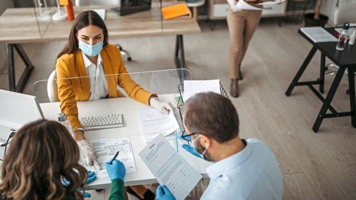 A group of people wearing protective masks at a desk.