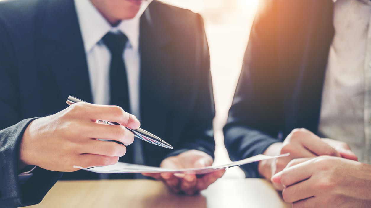Two business people signing documents at a table.