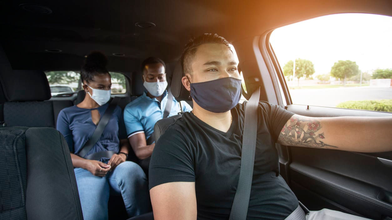 A group of people wearing face masks in a car.