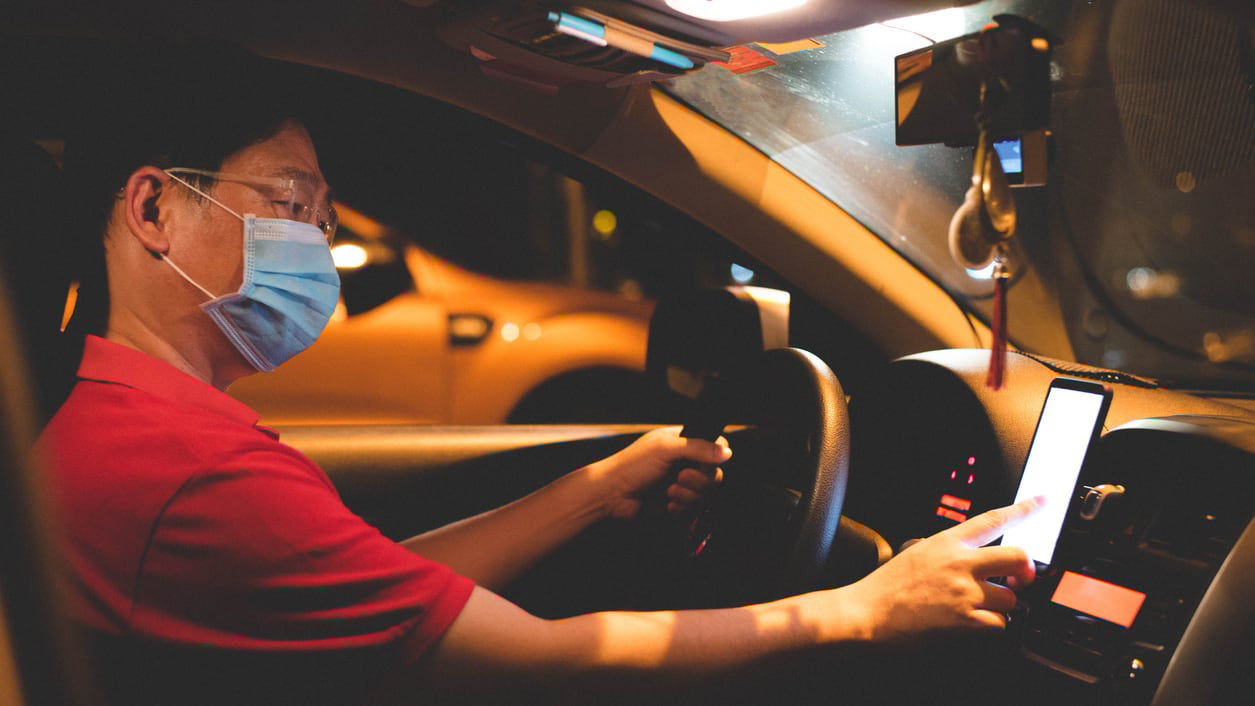 A man wearing a face mask while driving a car at night.