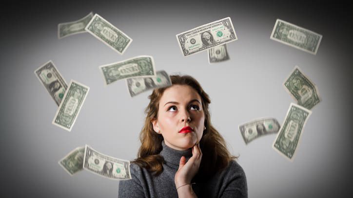 A woman looking up at money falling from the sky.