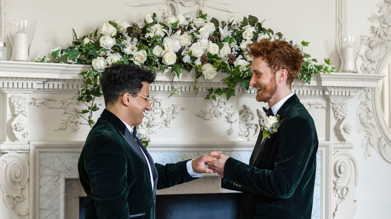 Two men shaking hands in front of a fireplace.