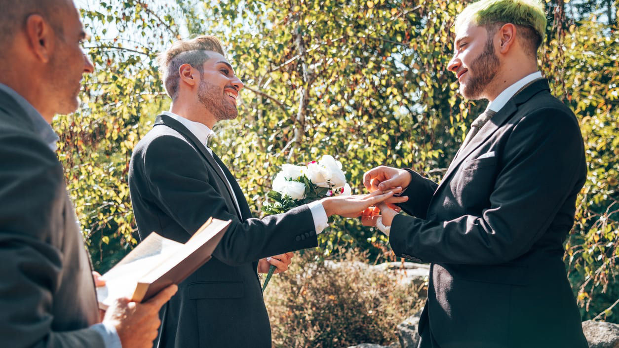 Two men are exchanging rings at a wedding ceremony.